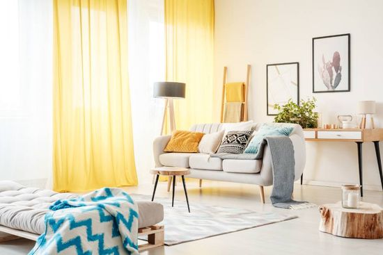 helles Wohnzimmer mit Sofa und gelben Vorhängen